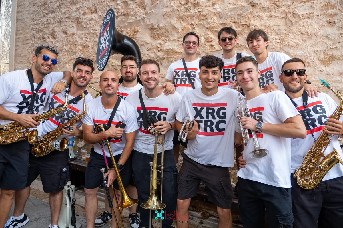 Los músicos de Xaranga El Truc posando con sus camisetas blancas y sus instrumentos