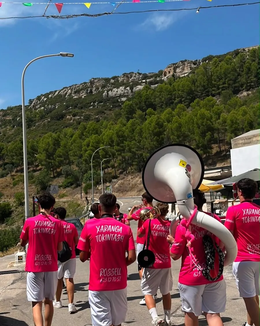 Xaranga Tokintash en pasacalles con tuba, camisetas rosas y montaña al fondo